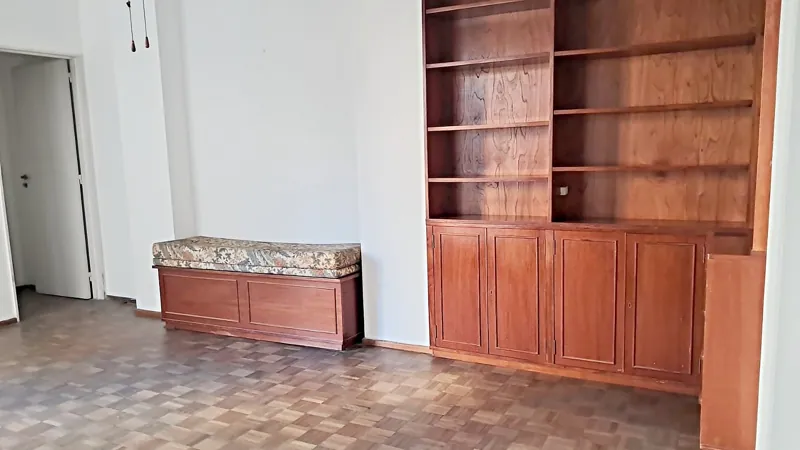 Living de departamento recién pintado de blanco con biblioteca de madera